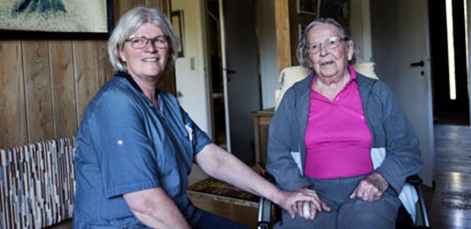 Hjælper holder hånd med ældre dame