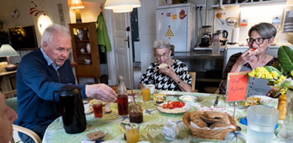 En mand og to kvinder sidder ved et bord og spiser