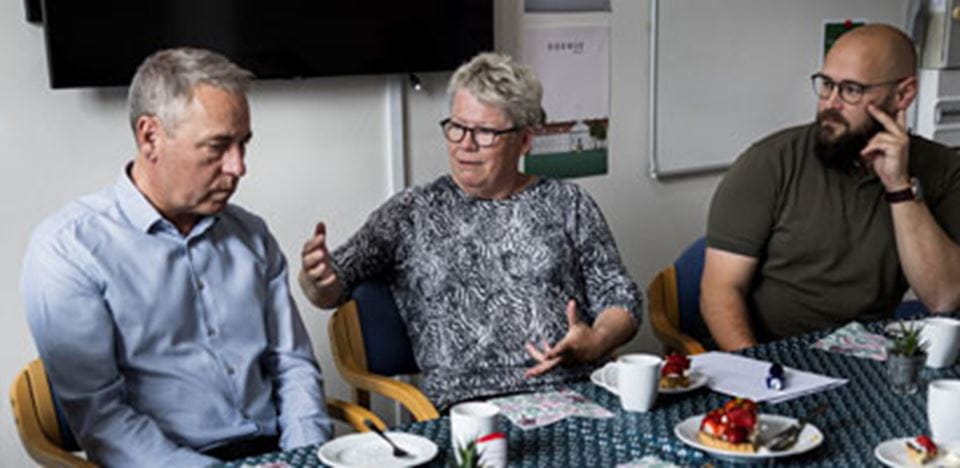 Tre ledere lytter og drøfter med hinanden i møde